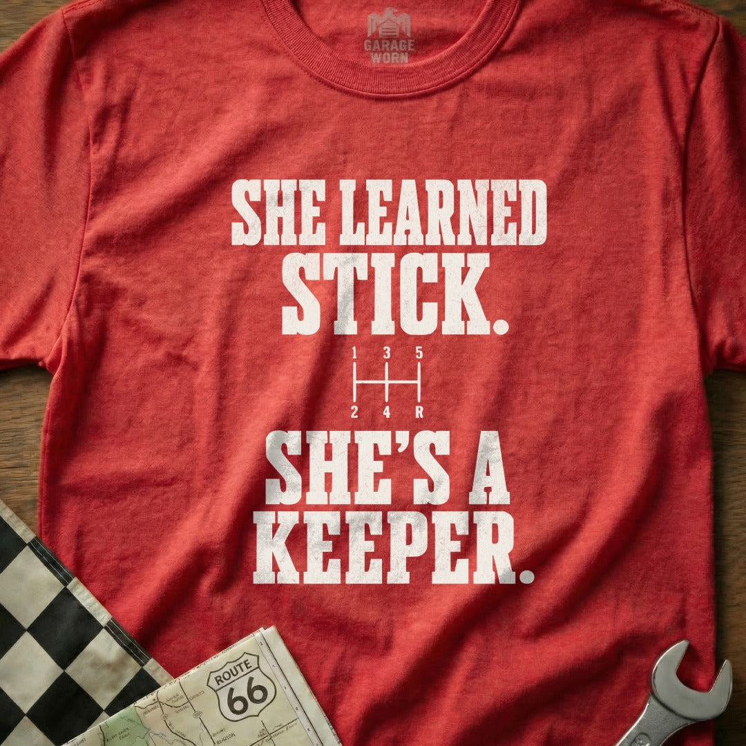 Red t-shirt with "She learned stick, she's a keeper" and a gear shift diagram.