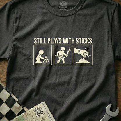 T-shirt graphic showing stick figures transitioning from campfire to playing with sticks and then operating a car gear shift.