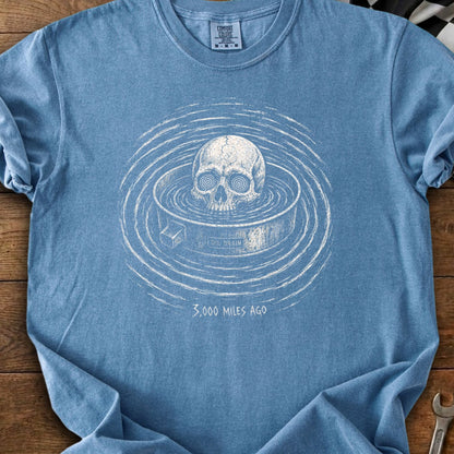 Skull in water with concentric rings, text "OIL DRAIN" and "3,000 MILES AGO".