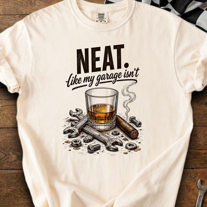 T-shirt with text "NEAT. Like my garage isn't", whiskey, cigar, and tools motif.