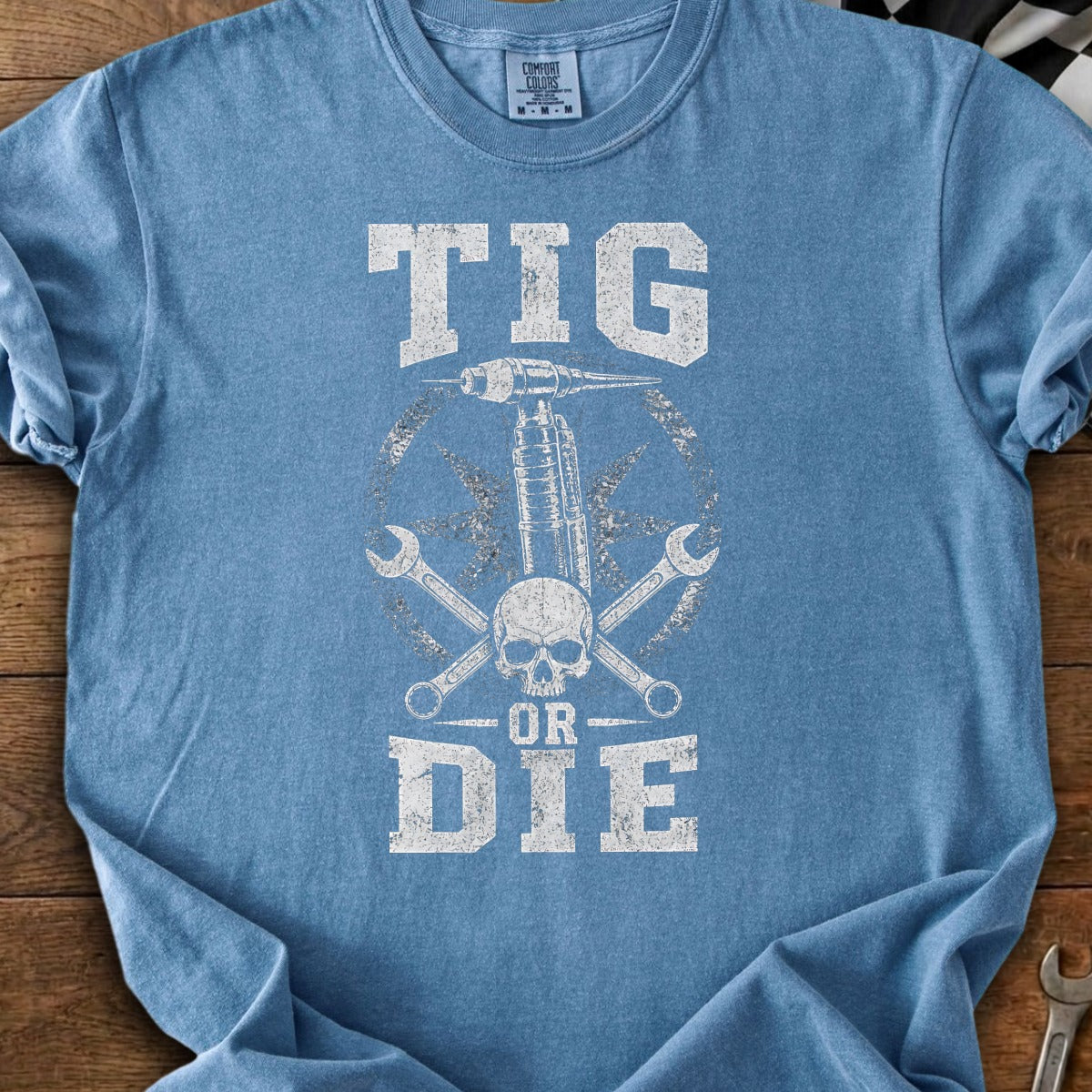 TIG welding torch, skull, wrenches, and "TIG OR DIE" text on a blue t-shirt.