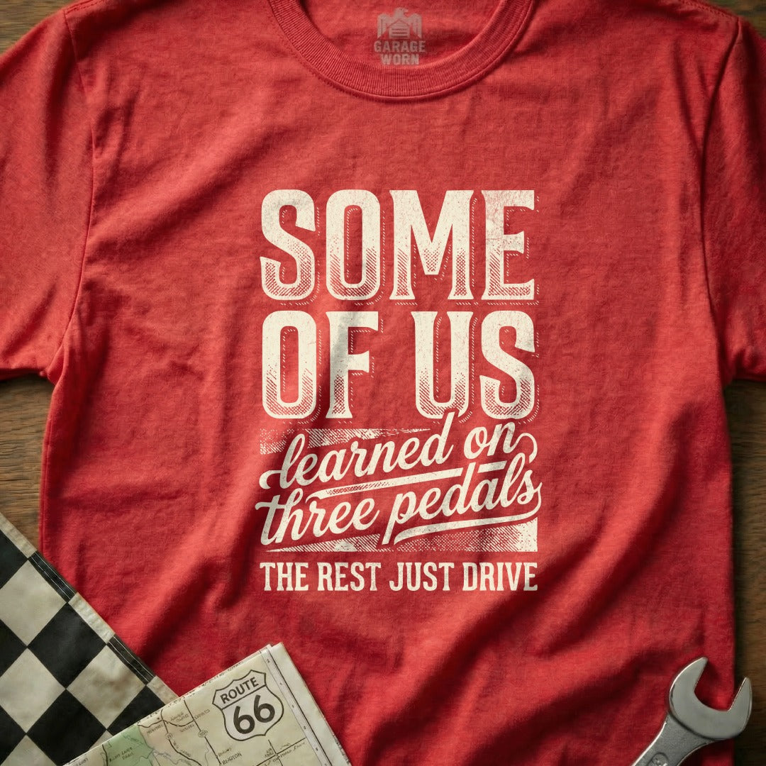 Red t-shirt with "SOME OF US learned on three pedals THE REST JUST DRIVE" text.