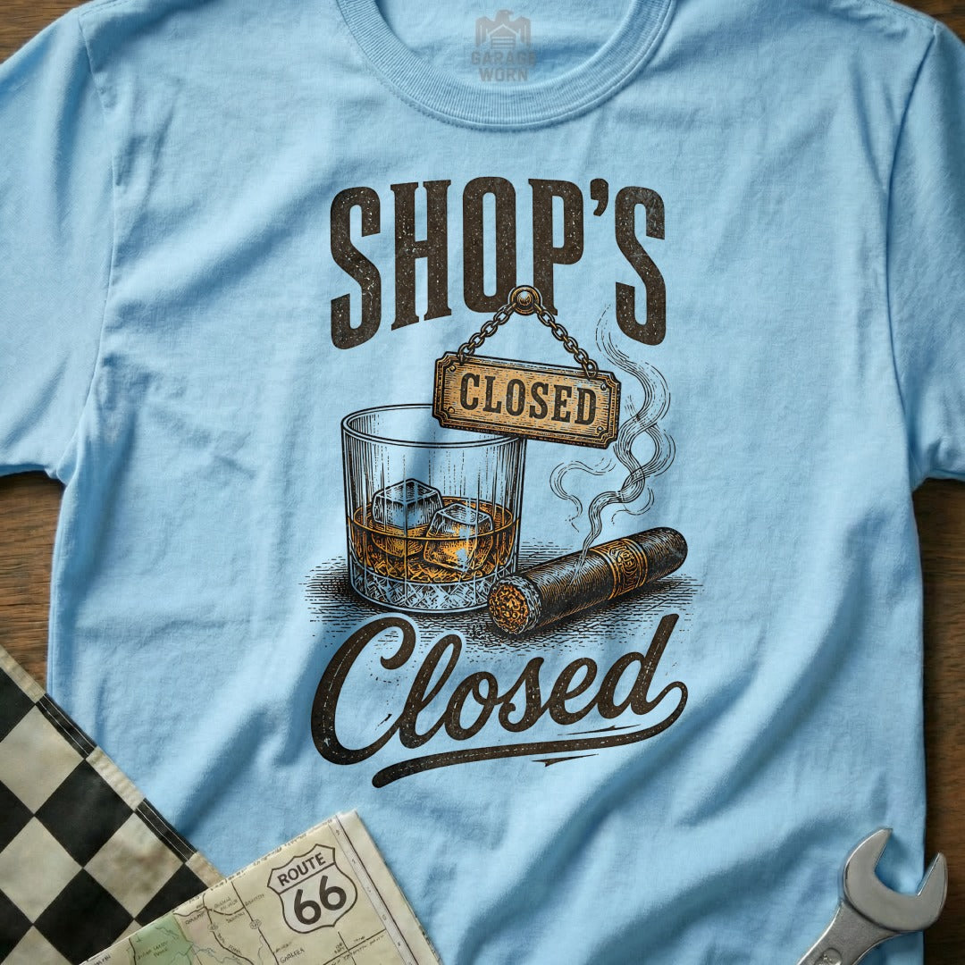 Light blue t-shirt with "SHOP'S CLOSED" graphic, featuring a glass of whiskey and a cigar.