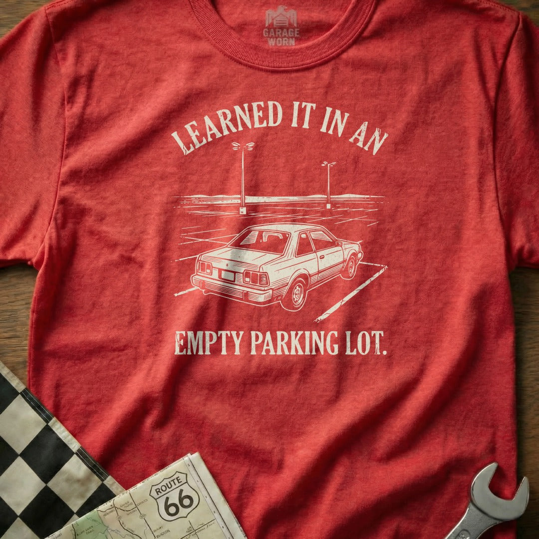 Red t-shirt with white text and drawing of a car in a parking lot.