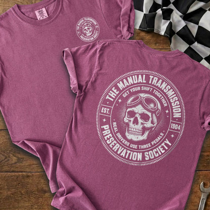 Maroon t-shirt with circular graphic of skull wearing goggles and text "The Manual Transmission Preservation Society".