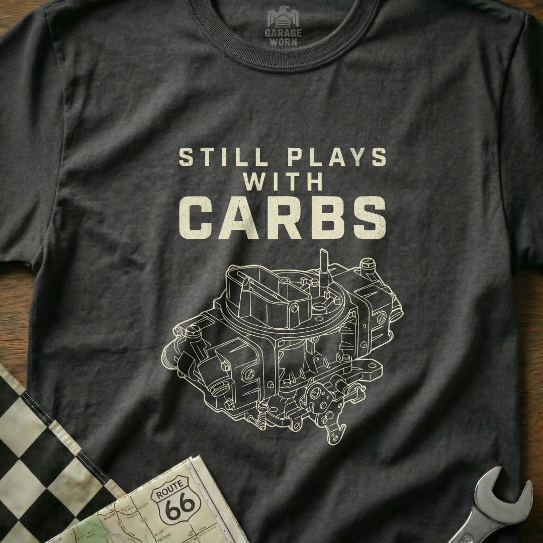 Dark t-shirt with white text "STILL PLAYS WITH CARBS" and carburetor graphic.