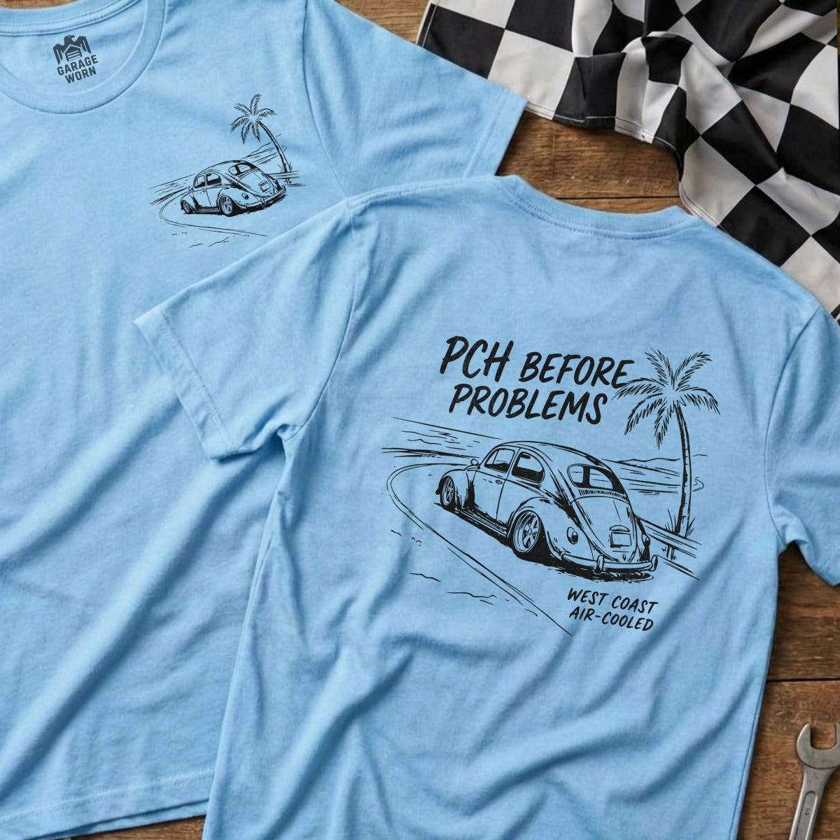 Light blue t-shirt with vintage car driving on coastal road, "PCH BEFORE PROBLEMS WEST COAST AIR-COOLED" text.