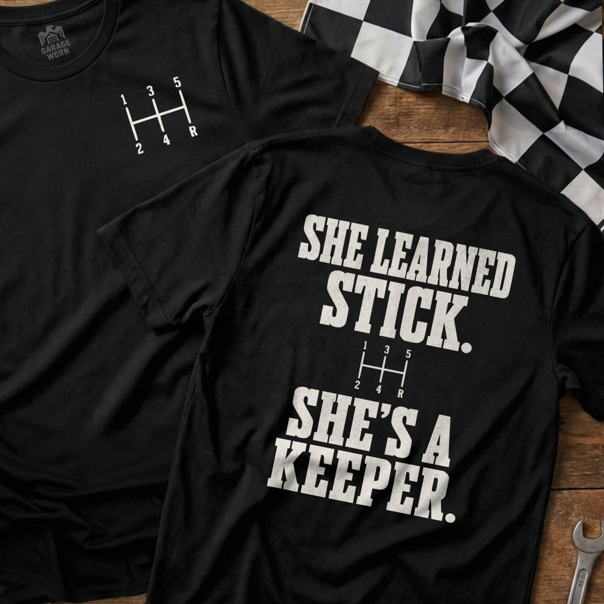 Black t-shirt with gear shift graphic and text "She Learned Stick. She's A Keeper."