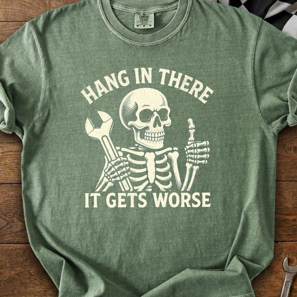 Skeleton holding wrench and giving thumbs up, with text "HANG IN THERE IT GETS WORSE".