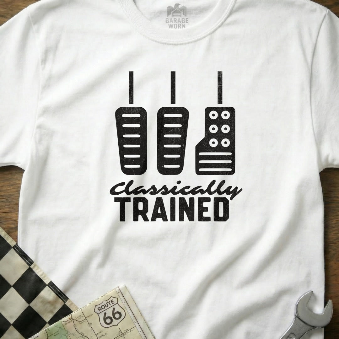 White t-shirt with black graphic of car pedals and text "Classically Trained."