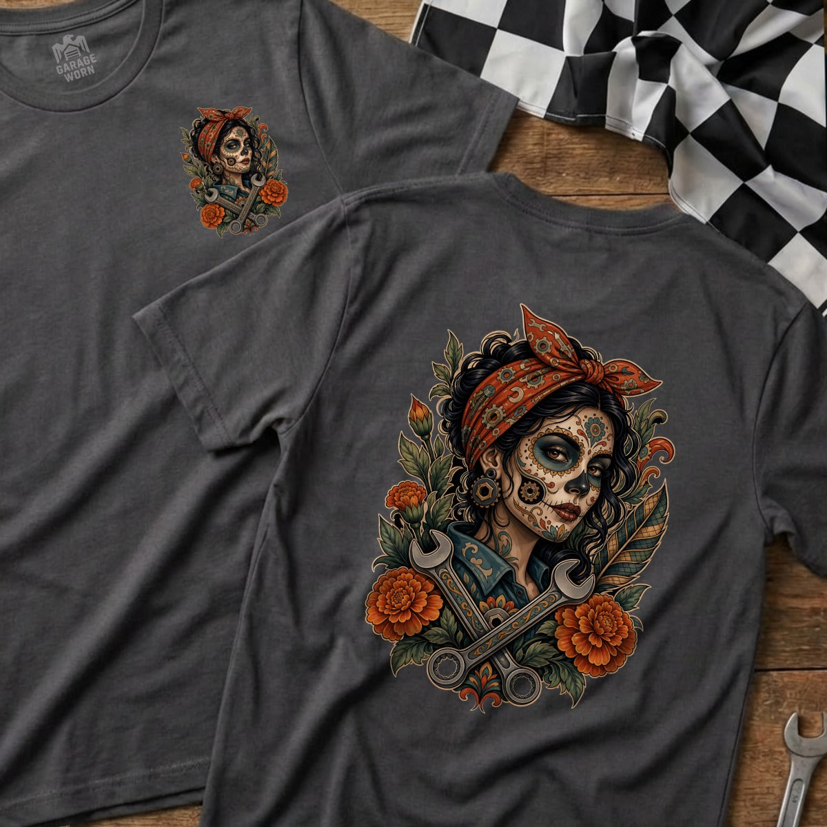 Dark gray t-shirts with a sugar skull woman illustration featuring wrenches and orange flowers.