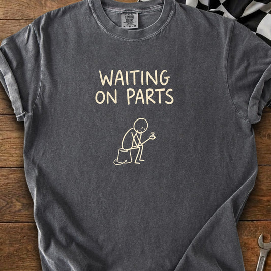 Dark gray t-shirt with text "WAITING ON PARTS" and a stick figure holding a bolt.