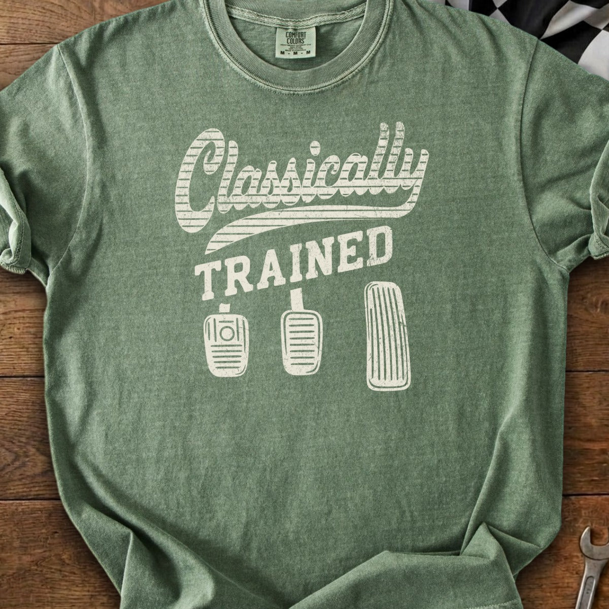 Green t-shirt with "Classically TRAINED" and three manual transmission pedals graphic.