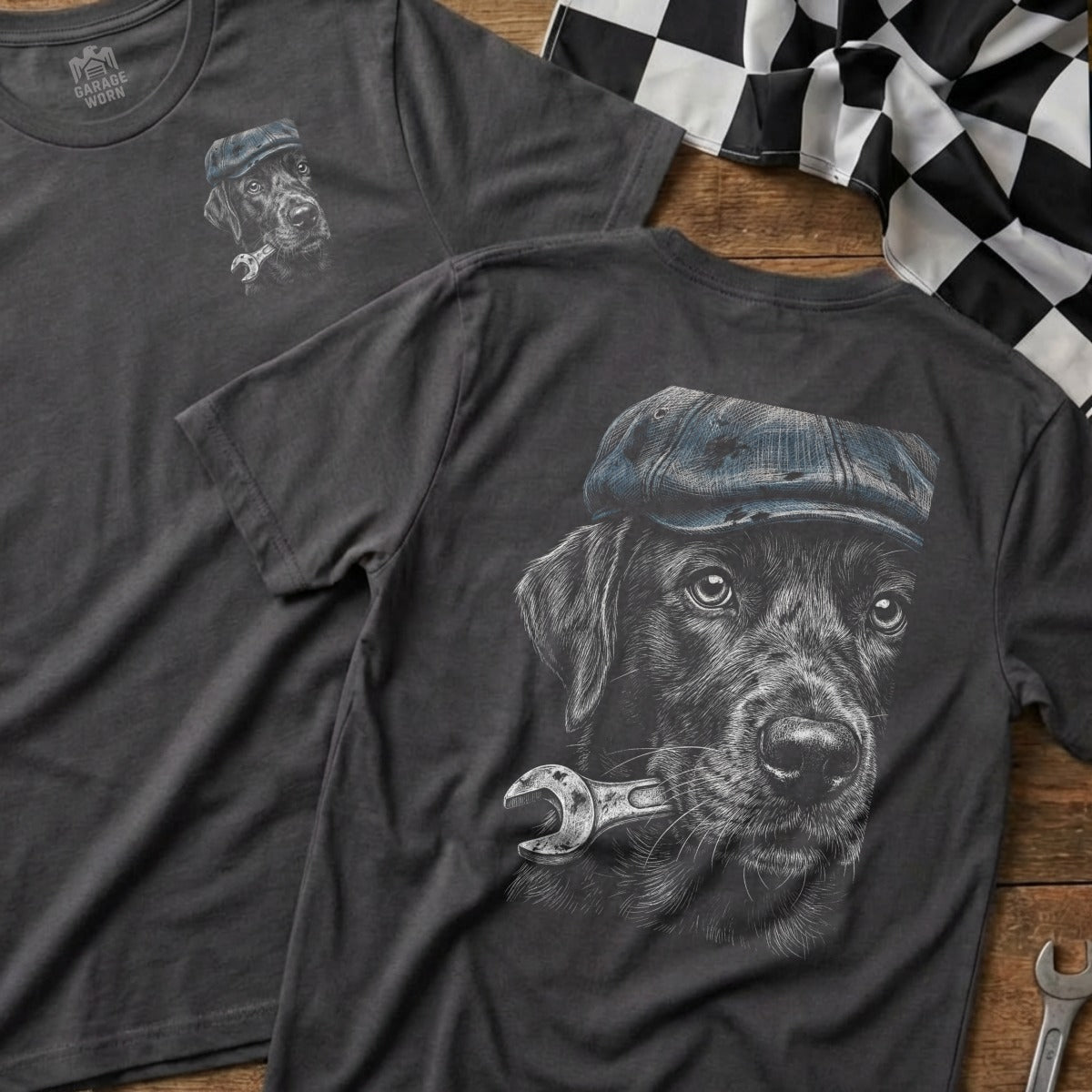 Black Labrador wearing a cap holds a wrench in its mouth, chest design.