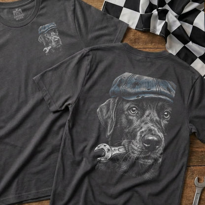 Black Labrador wearing a cap holds a wrench in its mouth, chest design.