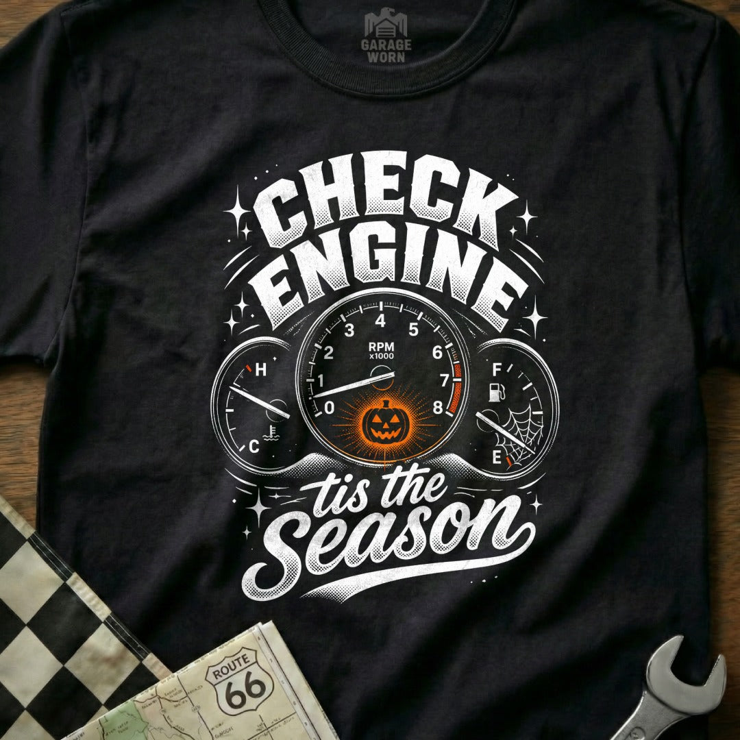 Black t-shirt with white text "Check Engine 'tis the Season" and dashboard gauges.