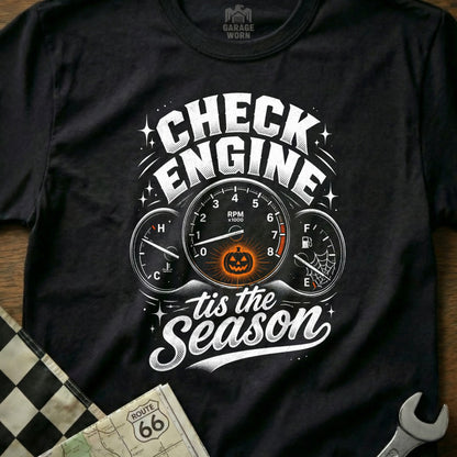 Black t-shirt with white text "Check Engine 'tis the Season" and dashboard gauges.