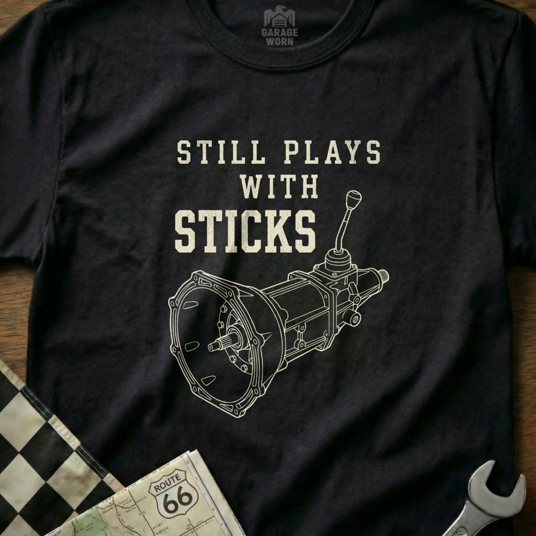 T-shirt with "Still Plays with Sticks" and manual transmission diagram.