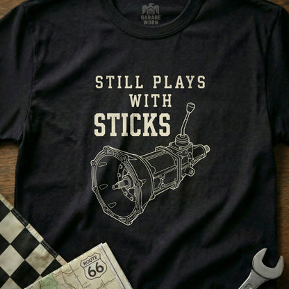 T-shirt with "Still Plays with Sticks" and manual transmission diagram.