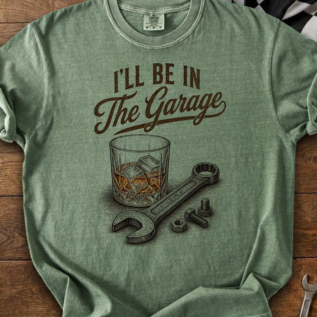 Green t-shirt with "I'll Be In The Garage" graphic, whiskey glass, wrench, and nuts.