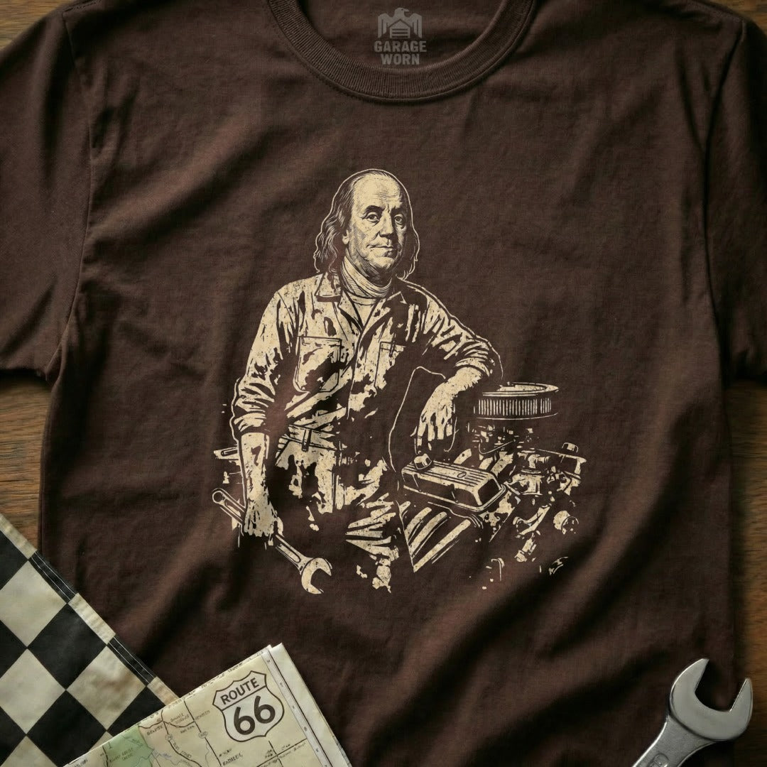 Benjamin Franklin in mechanic's overalls leans on an engine, holding a wrench.