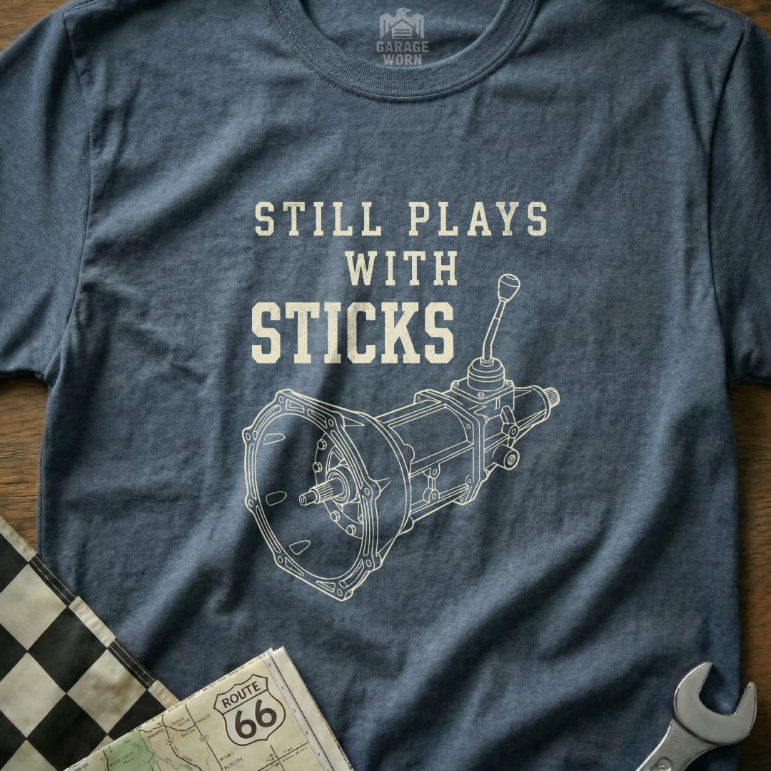 T-shirt with "Still Plays with Sticks" and a manual transmission diagram.
