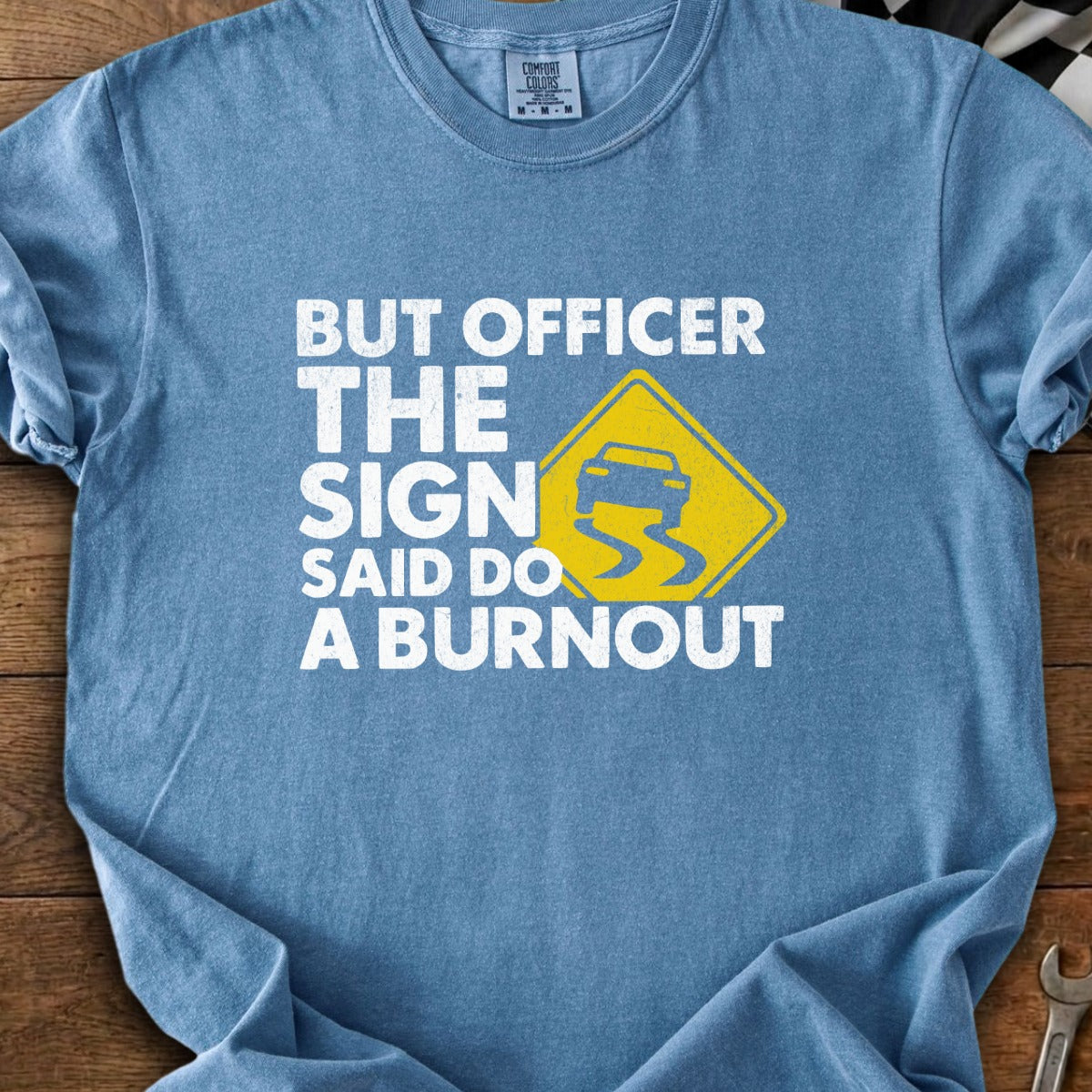 Blue t-shirt with white text: "BUT OFFICER THE SIGN SAID DO A BURNOUT."