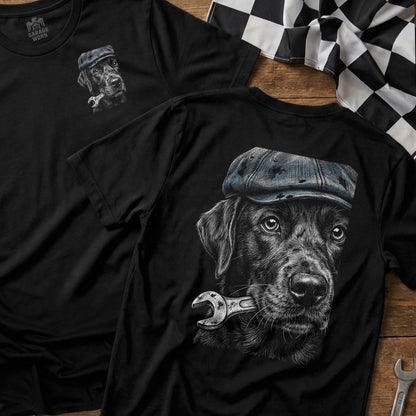 Black Labrador wearing a cap holds a wrench in its mouth.