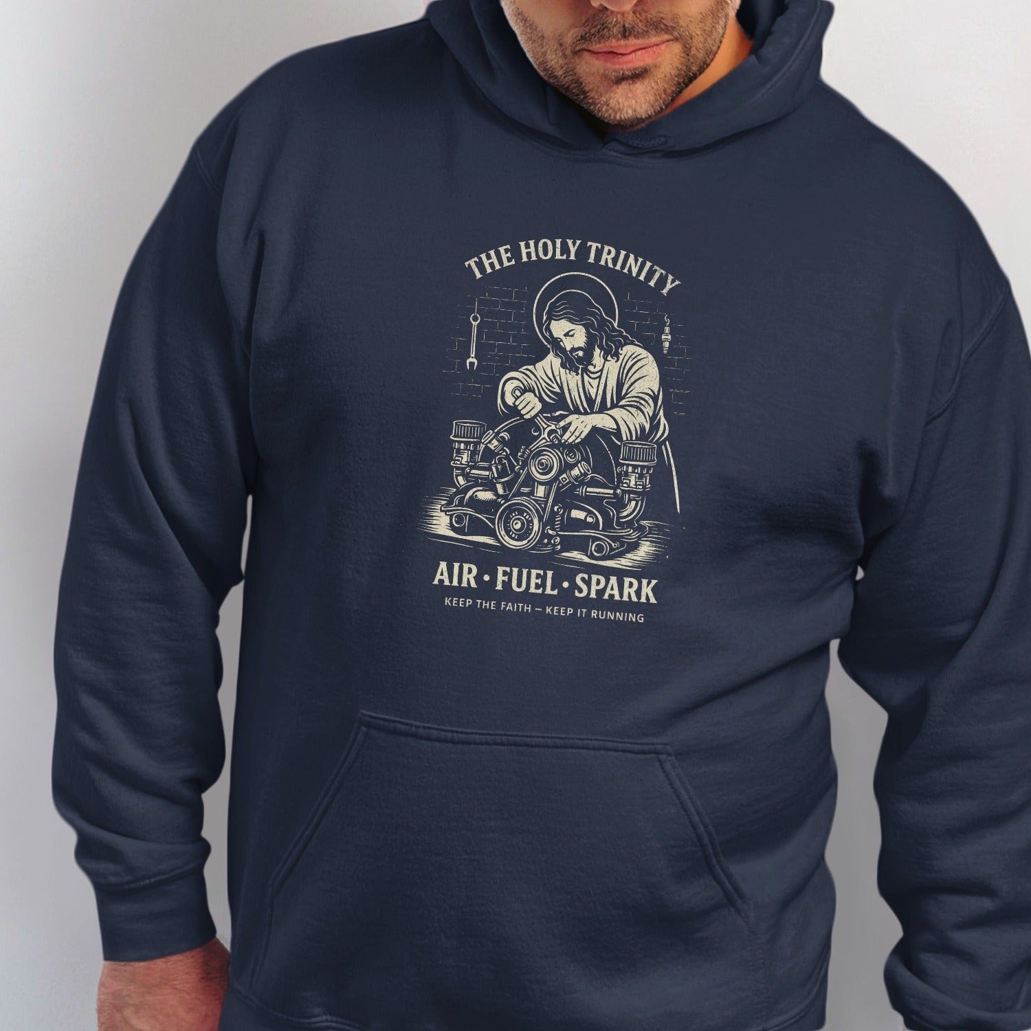 Navy hoodie with graphic of Jesus working on an engine, text reads "The Holy Trinity Air Fuel Spark".
