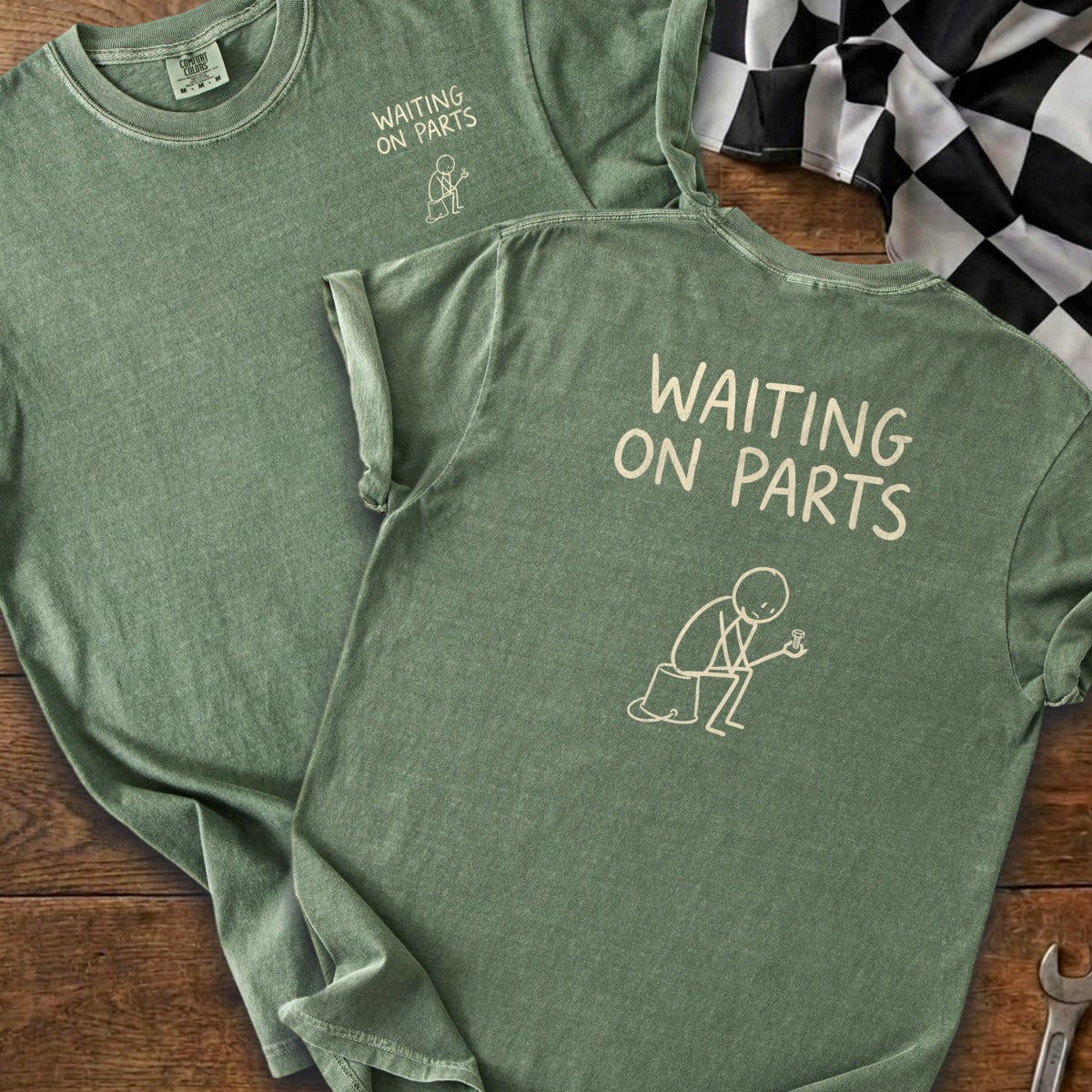 Green t-shirt with "WAITING ON PARTS" text and stick figure holding a small object.