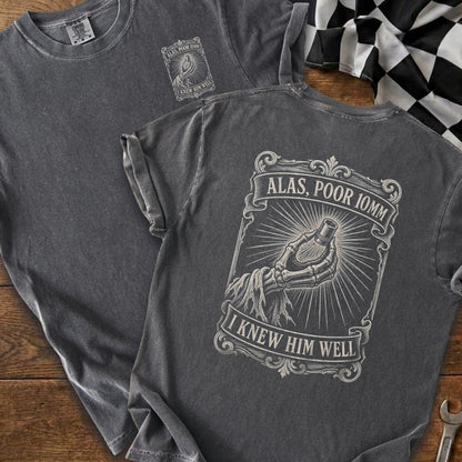 Charcoal t-shirt with skeleton hand holding a bolt and text "Alas, Poor 10mm".