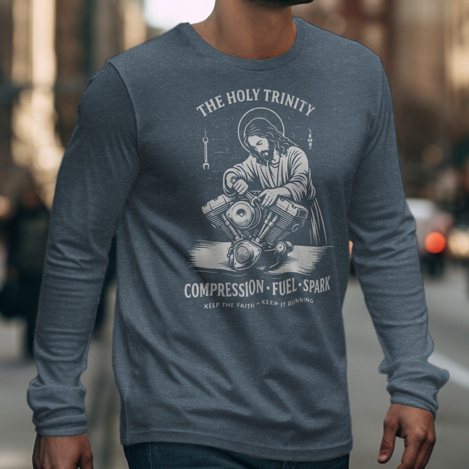 Jesus working on a motorcycle engine with text "THE HOLY TRINITY COMPRESSION FUEL SPARK".