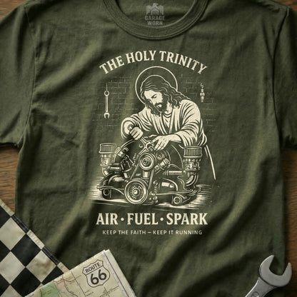 Olive t-shirt with Jesus working on an engine, text "The Holy Trinity Air Fuel Spark"