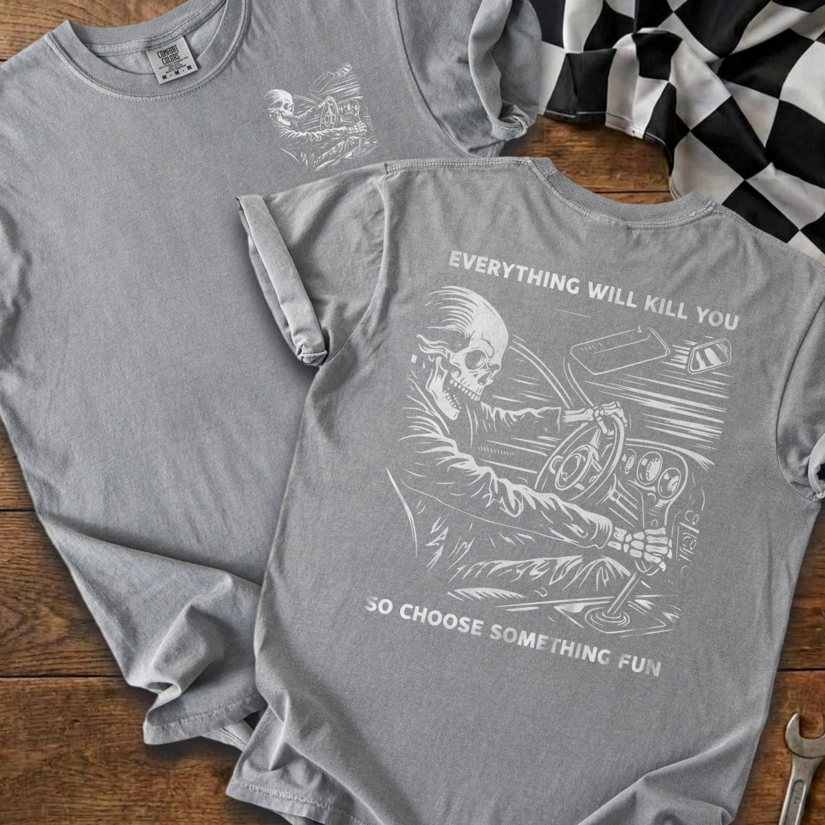Gray t-shirt with skeleton driving a car graphic and text.
