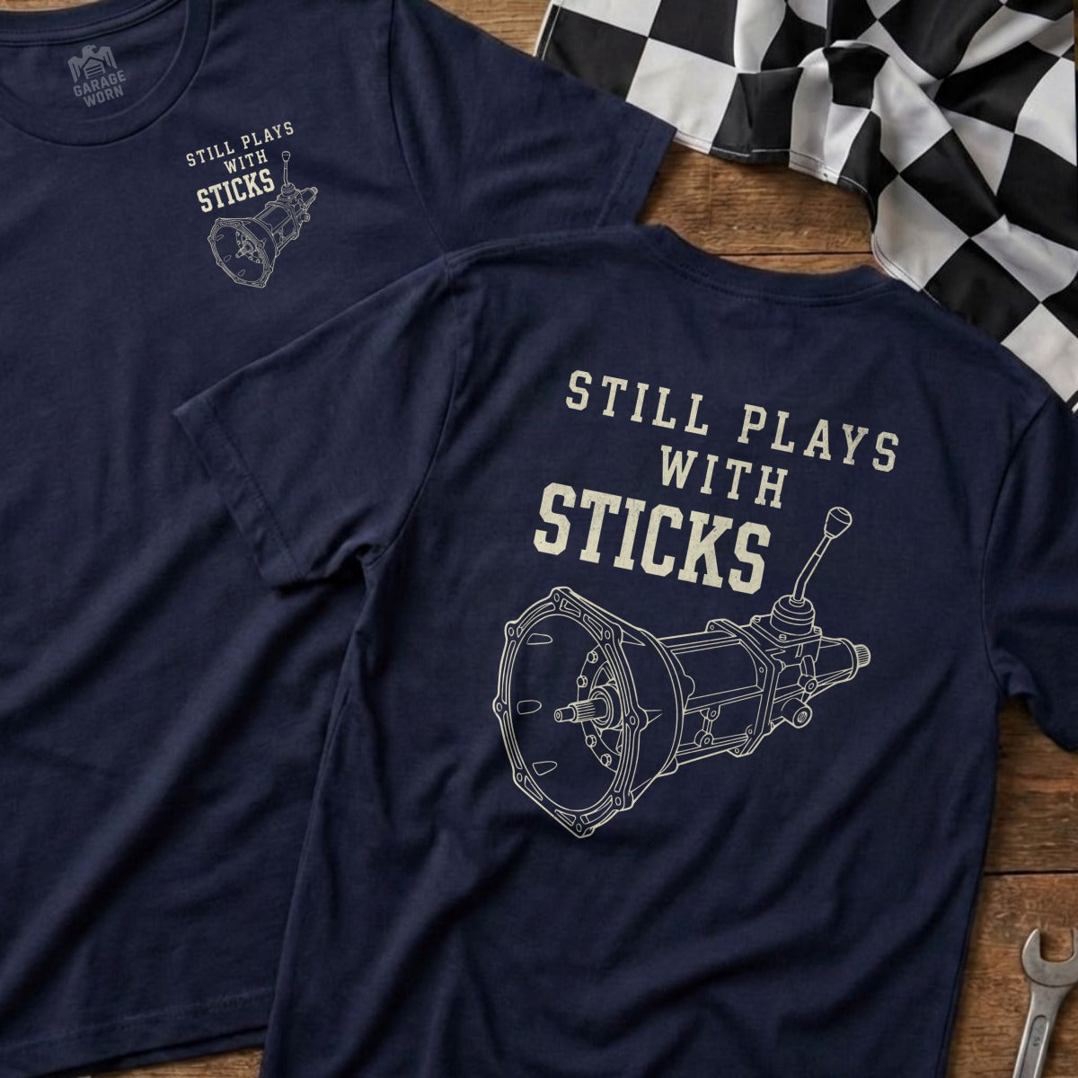 Navy t-shirt with "Still Plays With Sticks" and a manual transmission diagram.