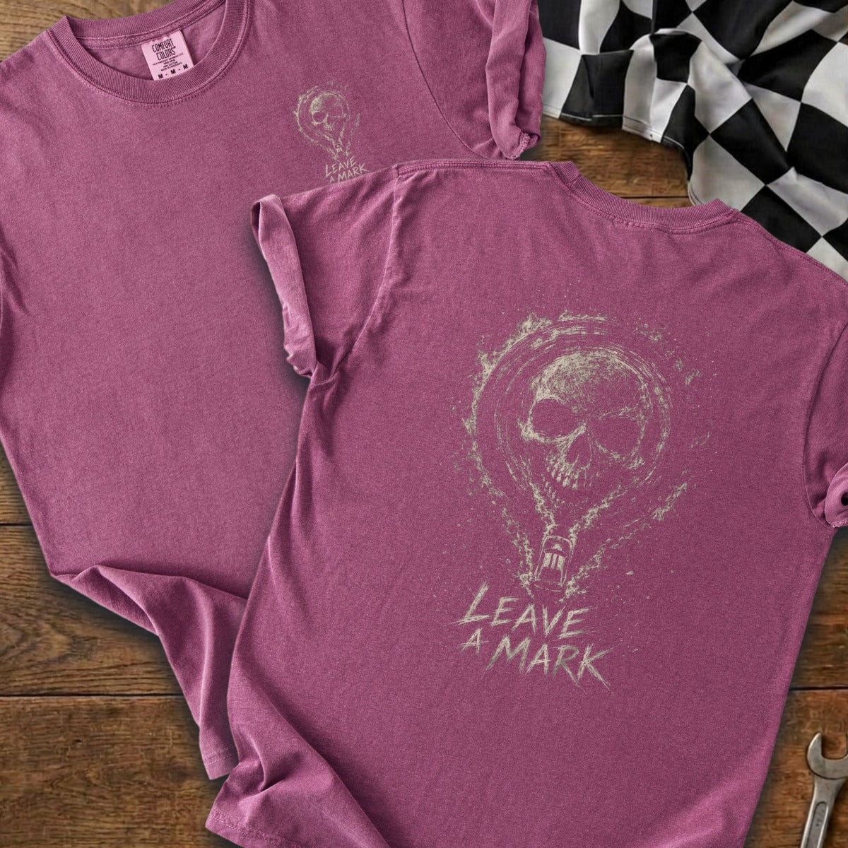 Two mauve t-shirts, one with a small skull and text, the other showing a large skull graphic and "LEAVE A MARK" text.