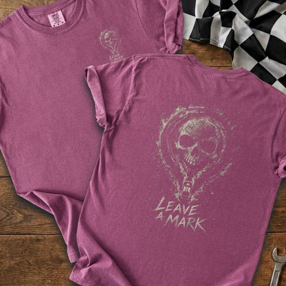 Two mauve t-shirts, one with a small skull and text, the other showing a large skull graphic and "LEAVE A MARK" text.