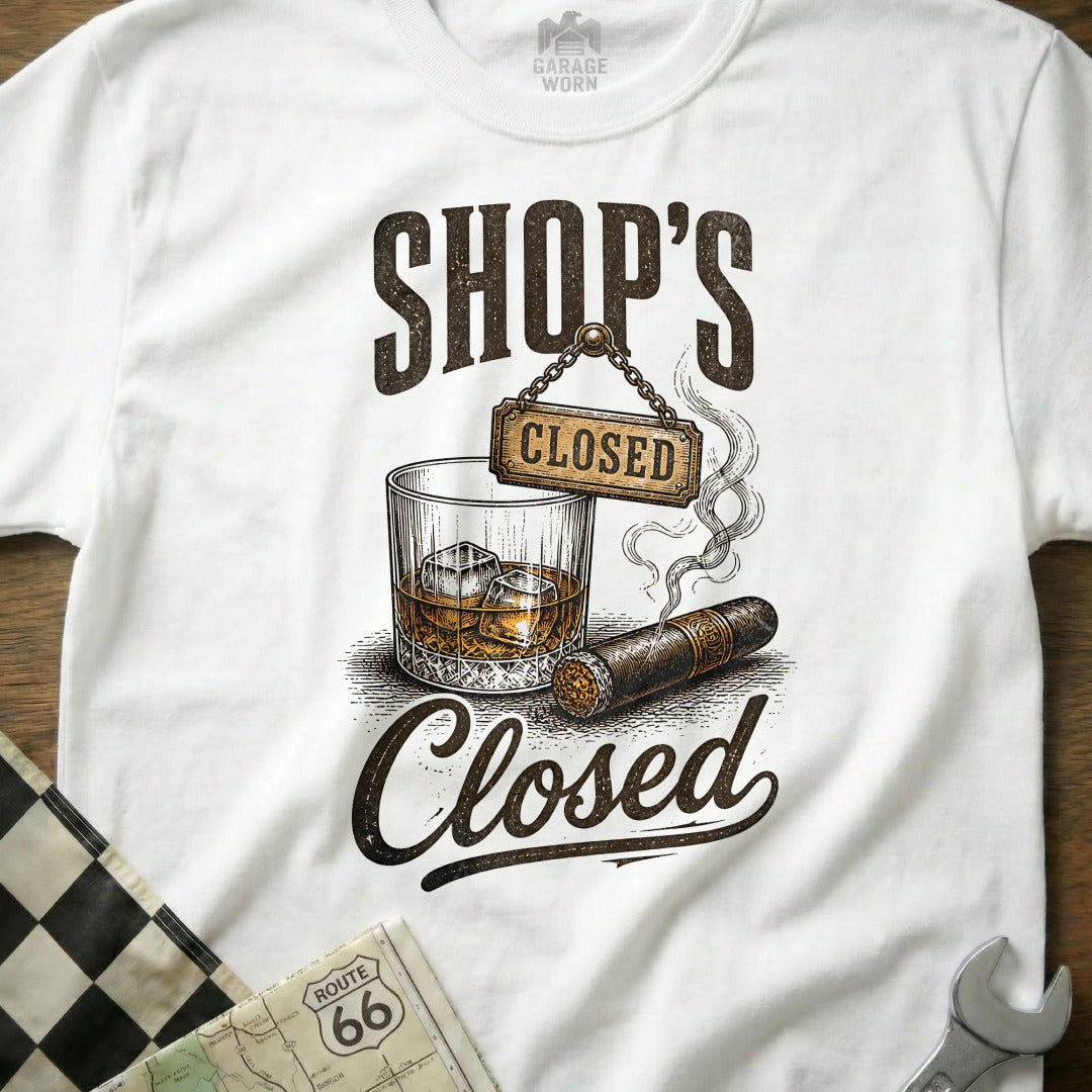 White t-shirt with "SHOP'S CLOSED" text, whiskey, cigar, and checkered flag graphic.