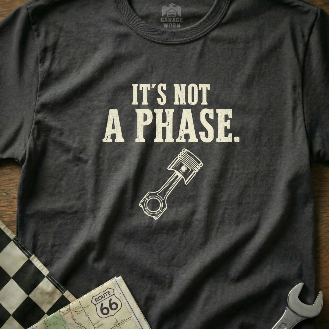Dark grey t-shirt with "IT'S NOT A PHASE." and piston graphic.
