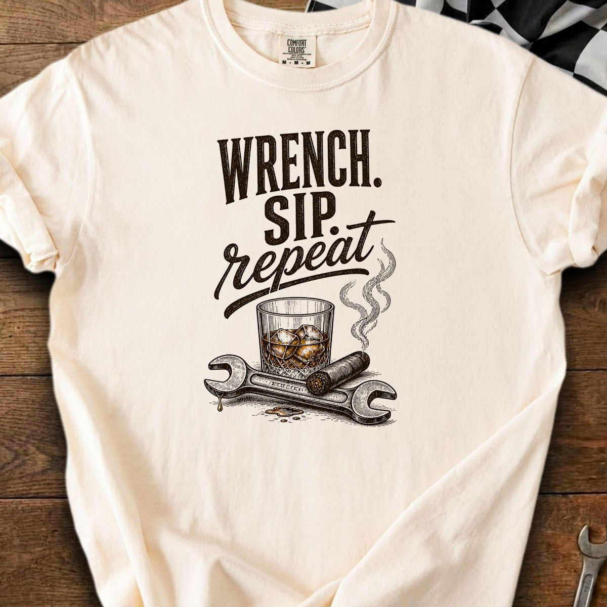 Cream t-shirt with "Wrench. Sip. Repeat." text, whiskey, cigar, and wrenches graphic.