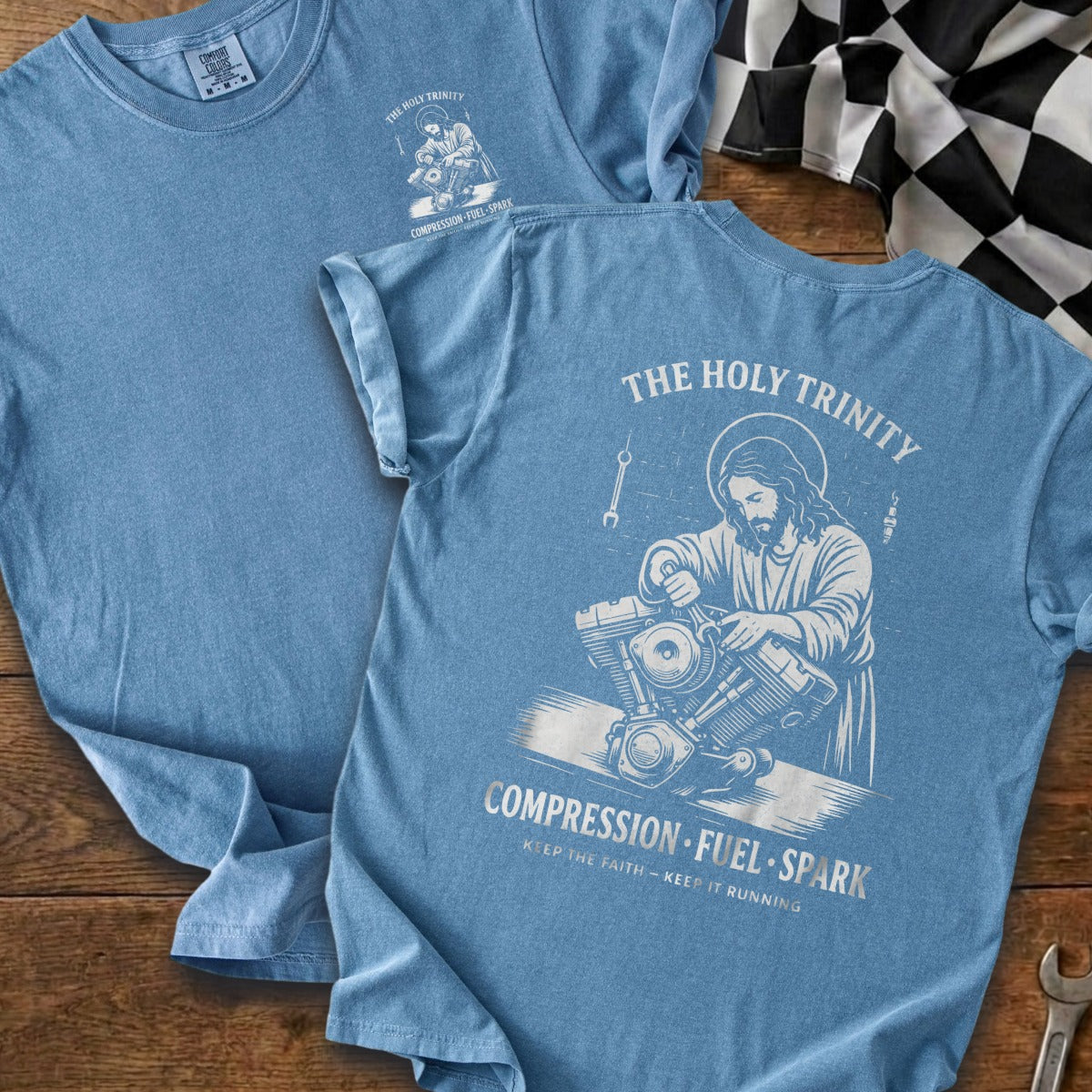 Blue t-shirt with "The Holy Trinity" text and graphic of Jesus working on a motorcycle engine.