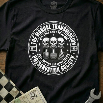 Black t-shirt with "Manual Transmission Preservation Society" circular graphic featuring skulls and pedals.
