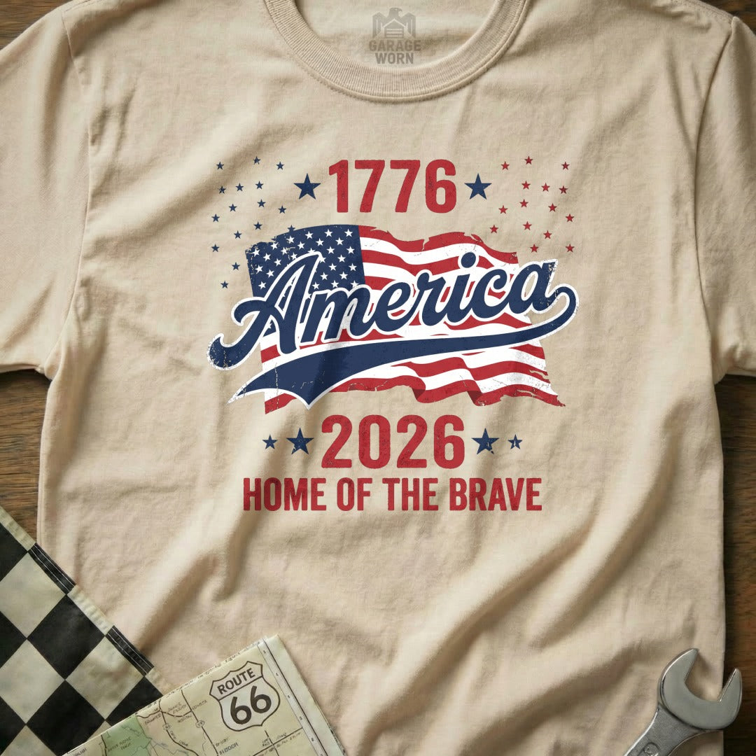 Cream t-shirt with America 1776 2026 Home of the Brave text and flag.