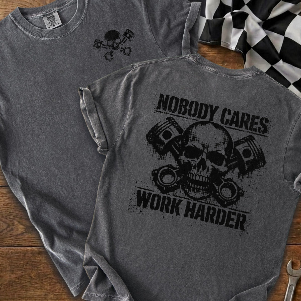 Dark gray t-shirt back with skull, pistons, and "Nobody Cares Work Harder" text.