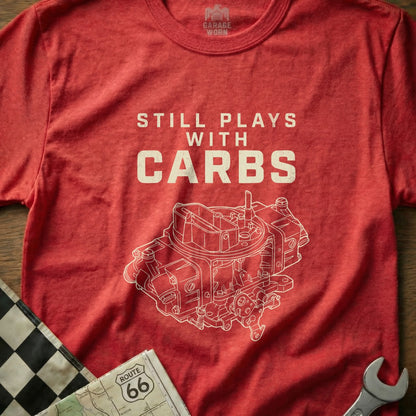 Red t-shirt with white graphic of a carburetor and text "STILL PLAYS WITH CARBS".