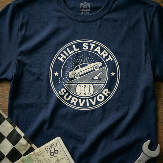 T-shirt graphic: "Hill Start Survivor" with manual car on incline.