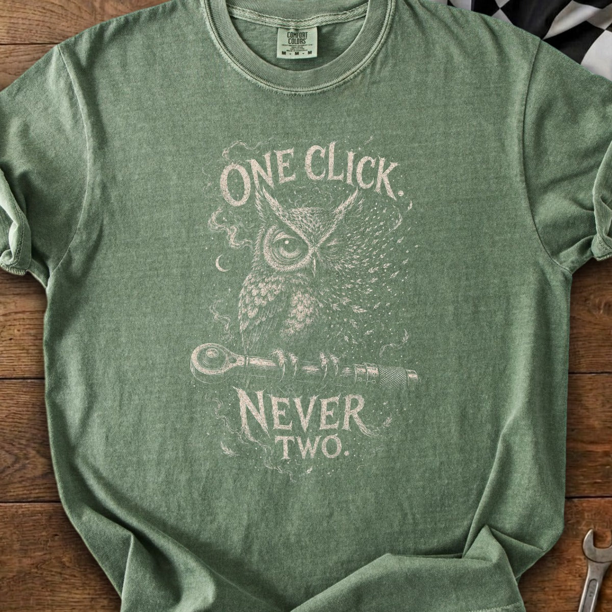 Green t-shirt with an owl graphic and text "ONE CLICK NEVER TWO".