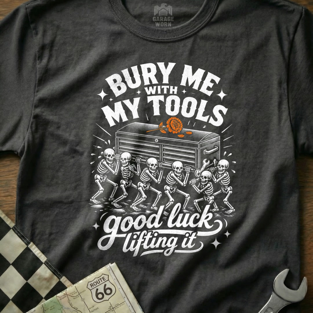 Dark gray t-shirt with white graphic of skeletons carrying a toolbox with text "Bury Me With My Tools Good Luck Lifting It".