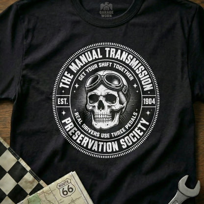 Black t-shirt with a circular graphic featuring a skull wearing goggles and text about manual transmissions.