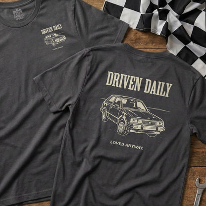 Dark grey t-shirt with "DRIVEN DAILY LOVED ANYWAY" and car graphic.
